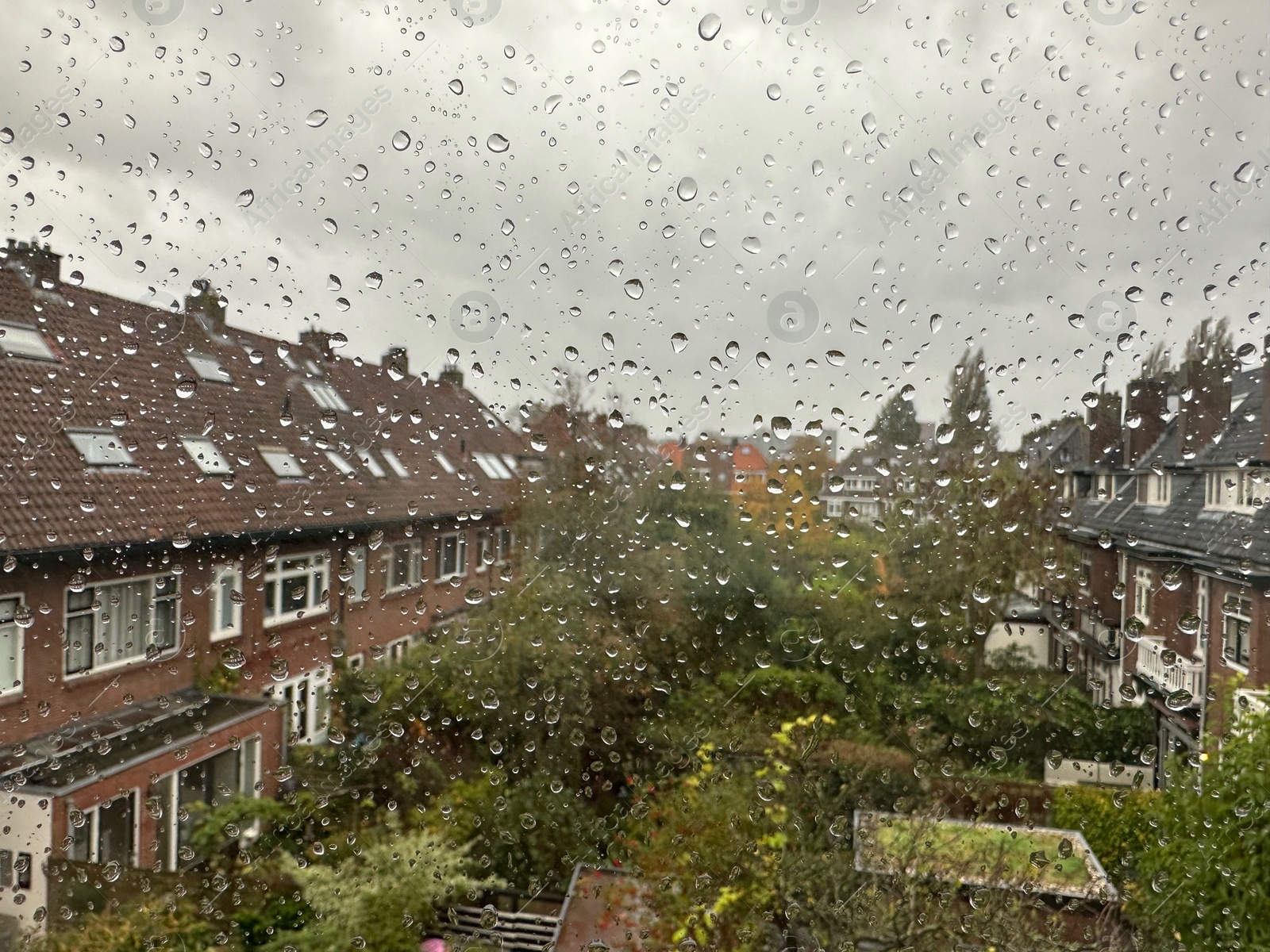 Photo of View on city street through window with water droplets on rainy day, closeup