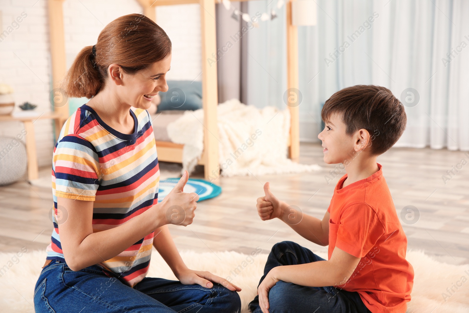 Photo of Hearing impaired mother and her child talking with help of sign language indoors