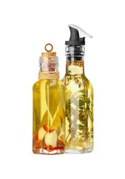 Photo of Glass bottles of cooking oil with spices and herbs on white background