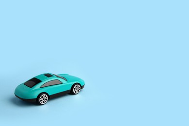 Photo of One bright car on light blue background, space for text. Children`s toy