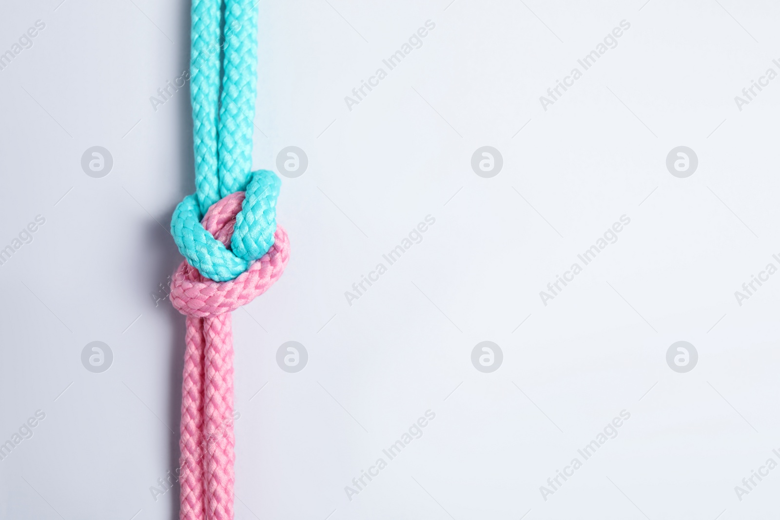 Photo of Colorful ropes tied together with knot isolated on white, top view. Unity concept