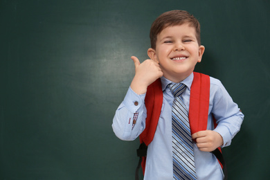 Photo of Cute little child near chalkboard, space for text. First time at school