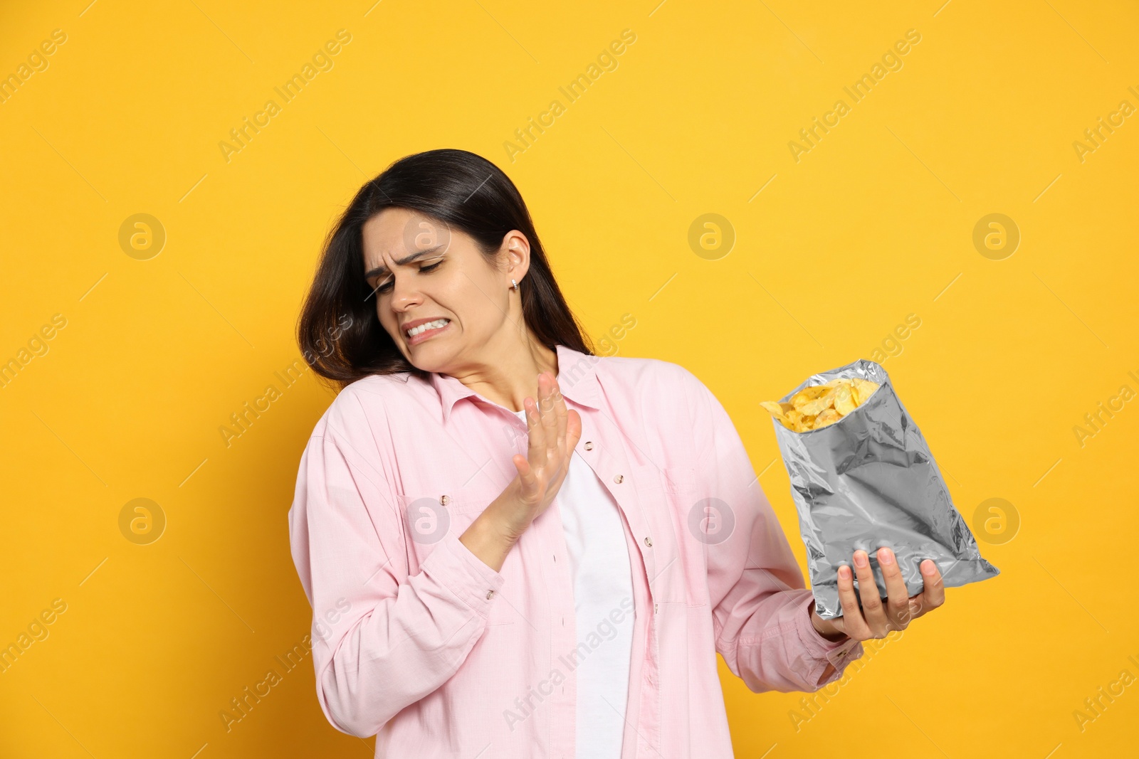 Photo of Beautiful woman refusing to eat potato chips on orange background