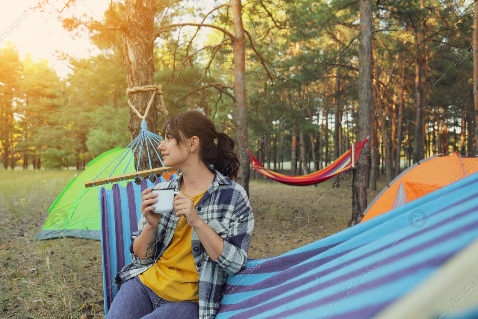 Photo of Woman with drink resting in comfortable hammock outdoors