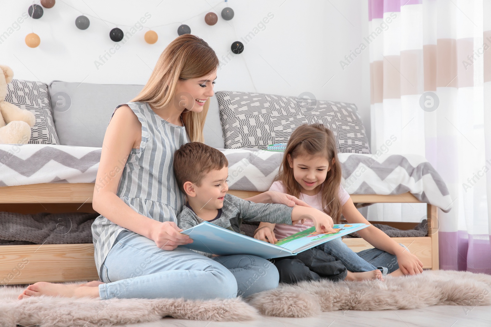 Photo of Nanny reading book to little children at home