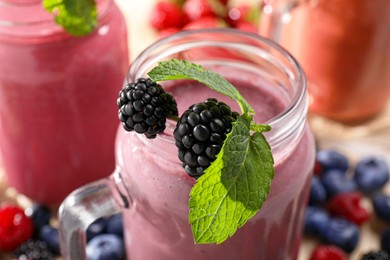 Photo of Mason jar of tasty smoothie with fresh blackberry and mint, closeup
