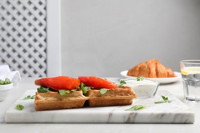 Photo of Fresh Belgian waffle with salmon and arugula on white table