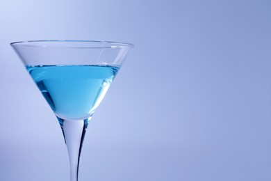 Martini glass with delicious cocktail on light blue background, space for text