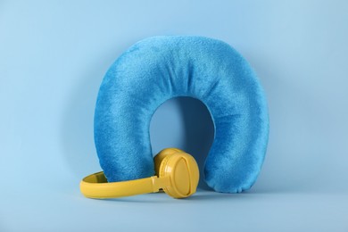 Photo of Travel pillow and headphones on light blue background