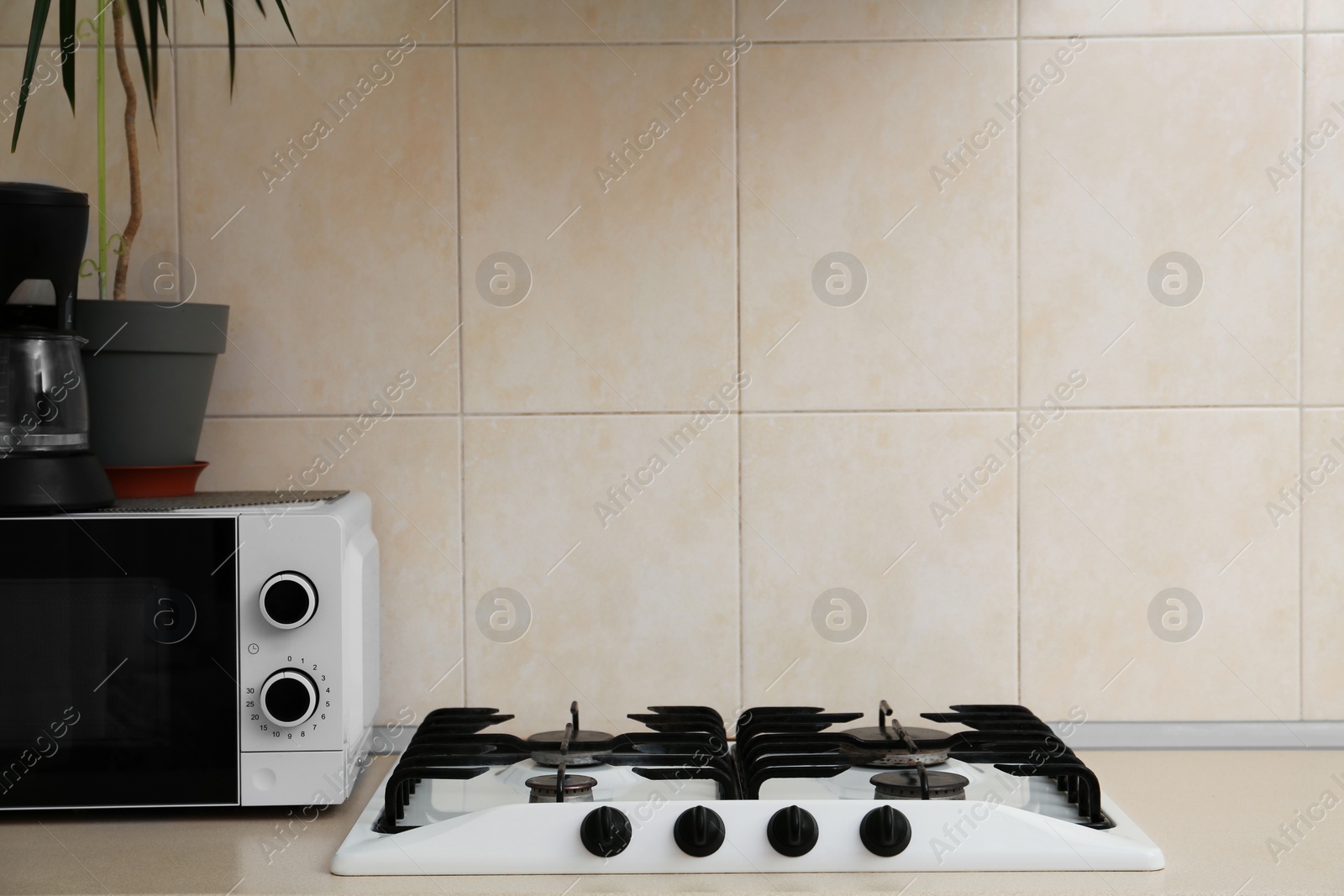 Photo of Modern gas cooktop and microwave oven in kitchen, space for text