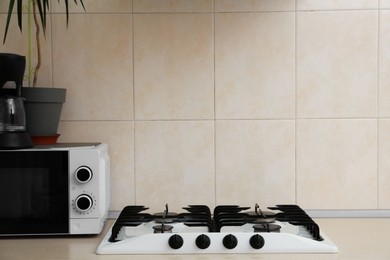 Photo of Modern gas cooktop and microwave oven in kitchen, space for text