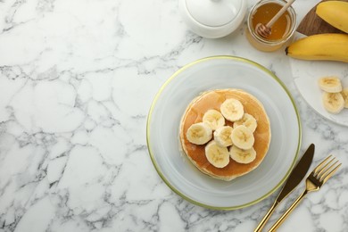 Photo of Delicious pancakes with bananas and honey served on white marble table, flat lay. Space for text