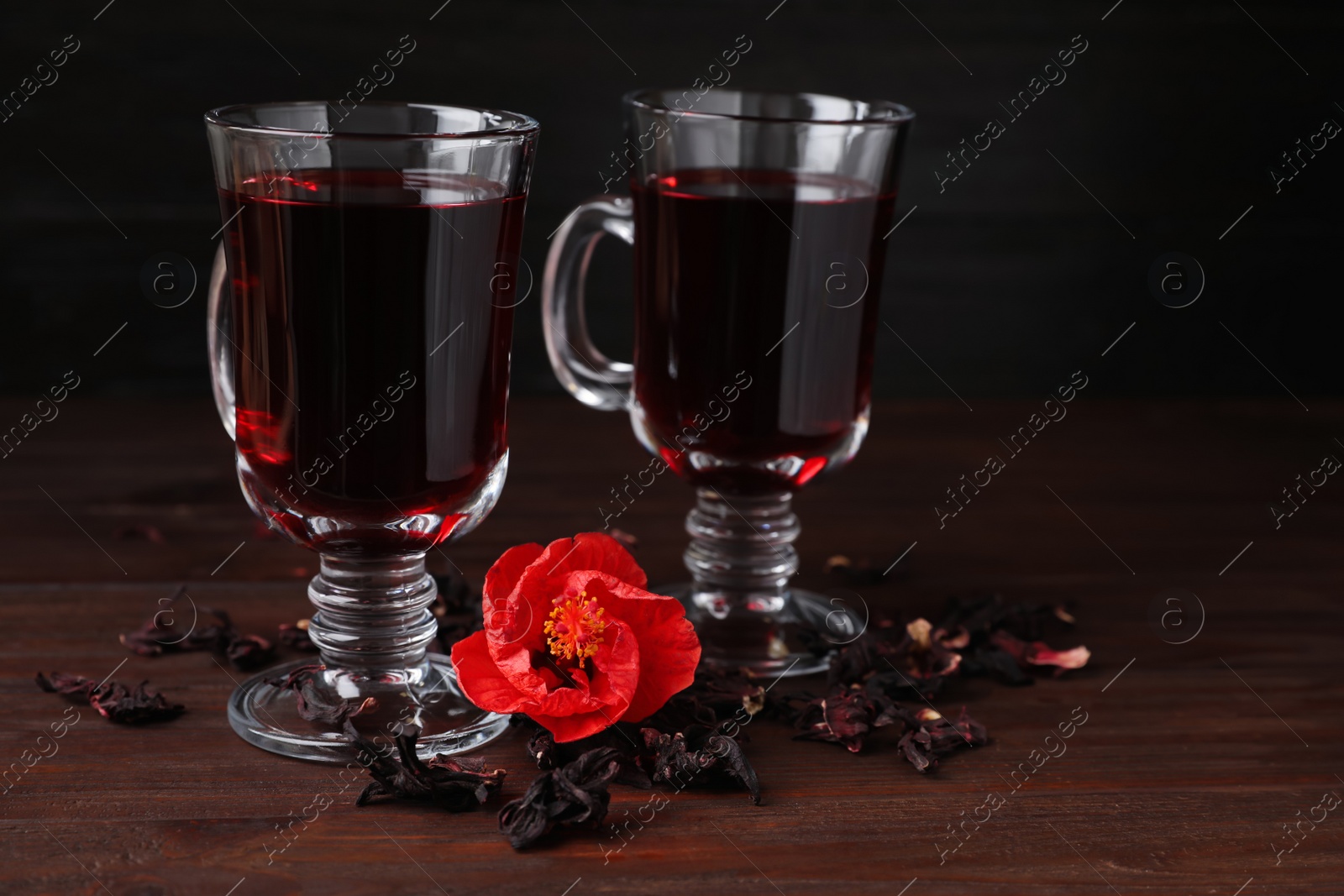 Photo of Delicious hibiscus tea and dry flowers on wooden table