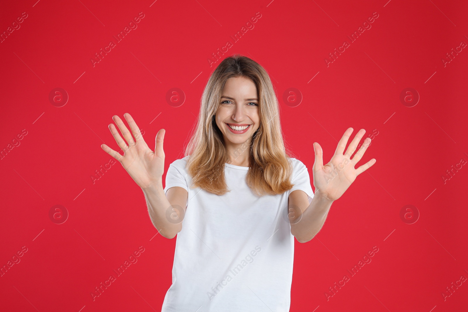 Photo of Woman showing number ten with her hands on red background