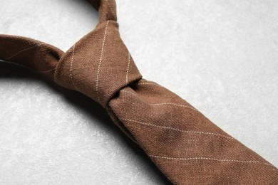 One striped necktie on light textured table, above view