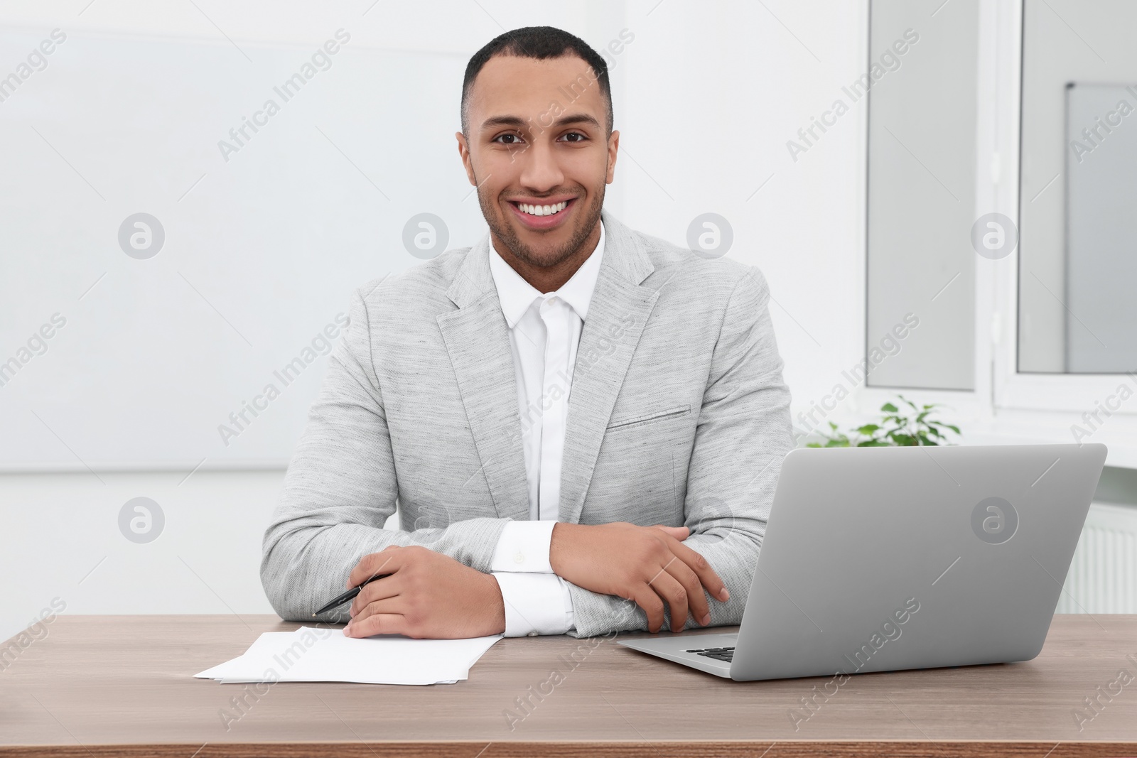 Photo of Happy young intern working at table in modern office