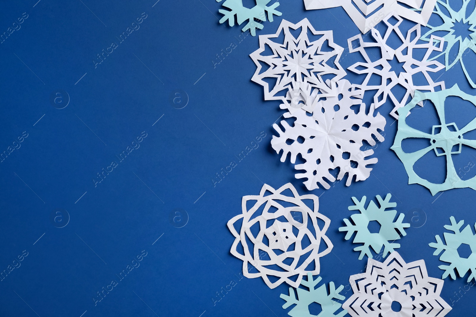 Photo of Many paper snowflakes on blue background, flat lay. Space for text