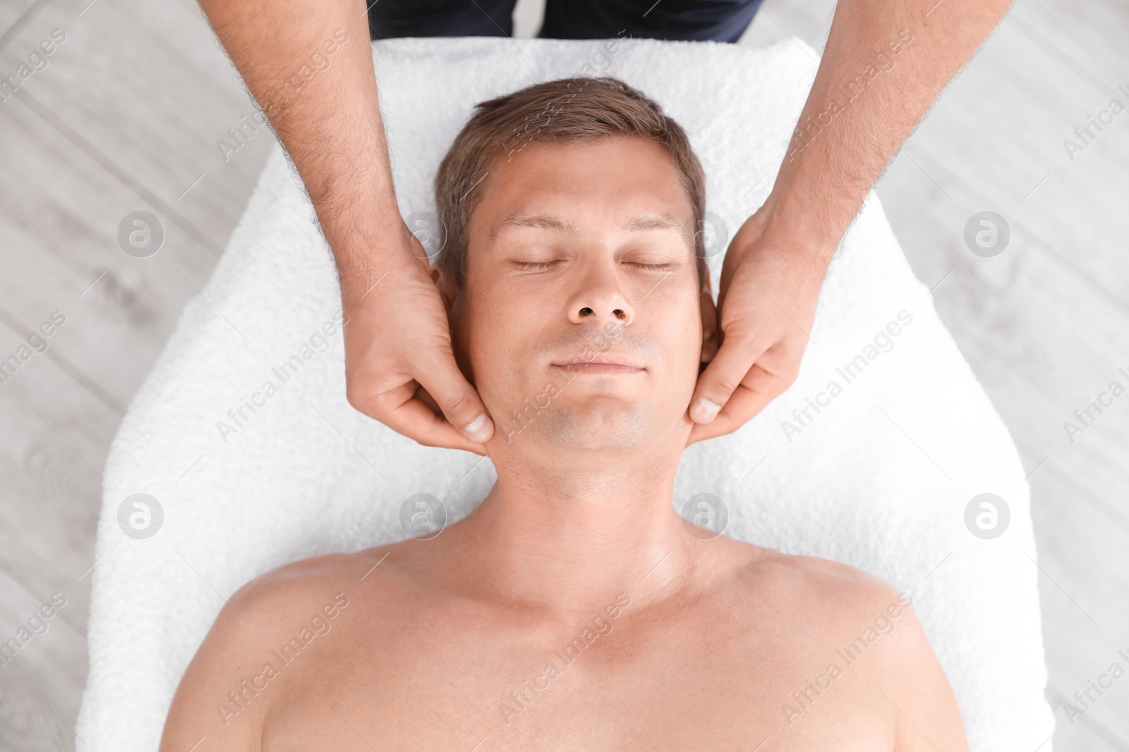 Photo of Relaxed man receiving head massage in wellness center, top view