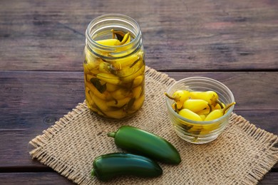 Photo of Fresh and pickled jalapeno peppers on wooden table