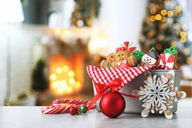 Image of Christmas cookies and ornaments on marble table in decorated room 