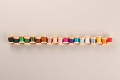 Different colorful sewing threads on light grey background, flat lay