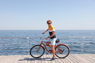 Attractive man riding bike near sea on sunny day