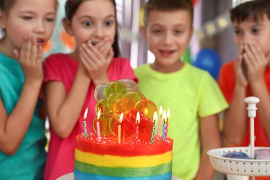 Children near cake with candles at birthday party indoors