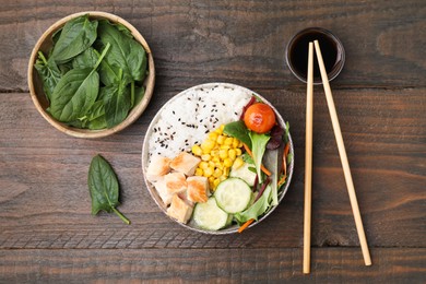 Delicious poke bowl with meat, rice, vegetables and greens served on wooden table, flat lay