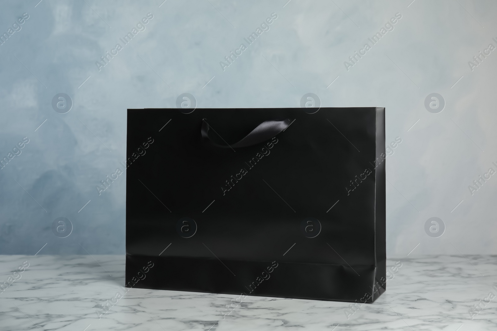 Photo of Paper shopping bag on table against color background. Mock up for design