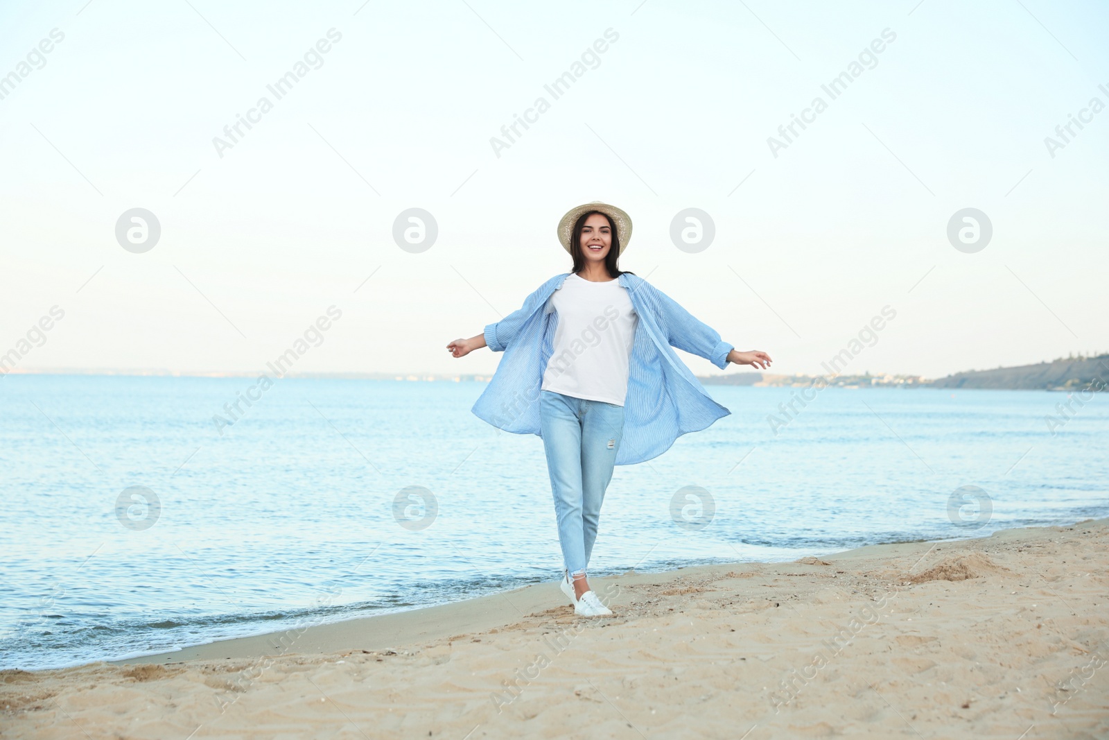 Photo of Beautiful young woman in casual outfit on beach