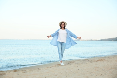 Photo of Beautiful young woman in casual outfit on beach