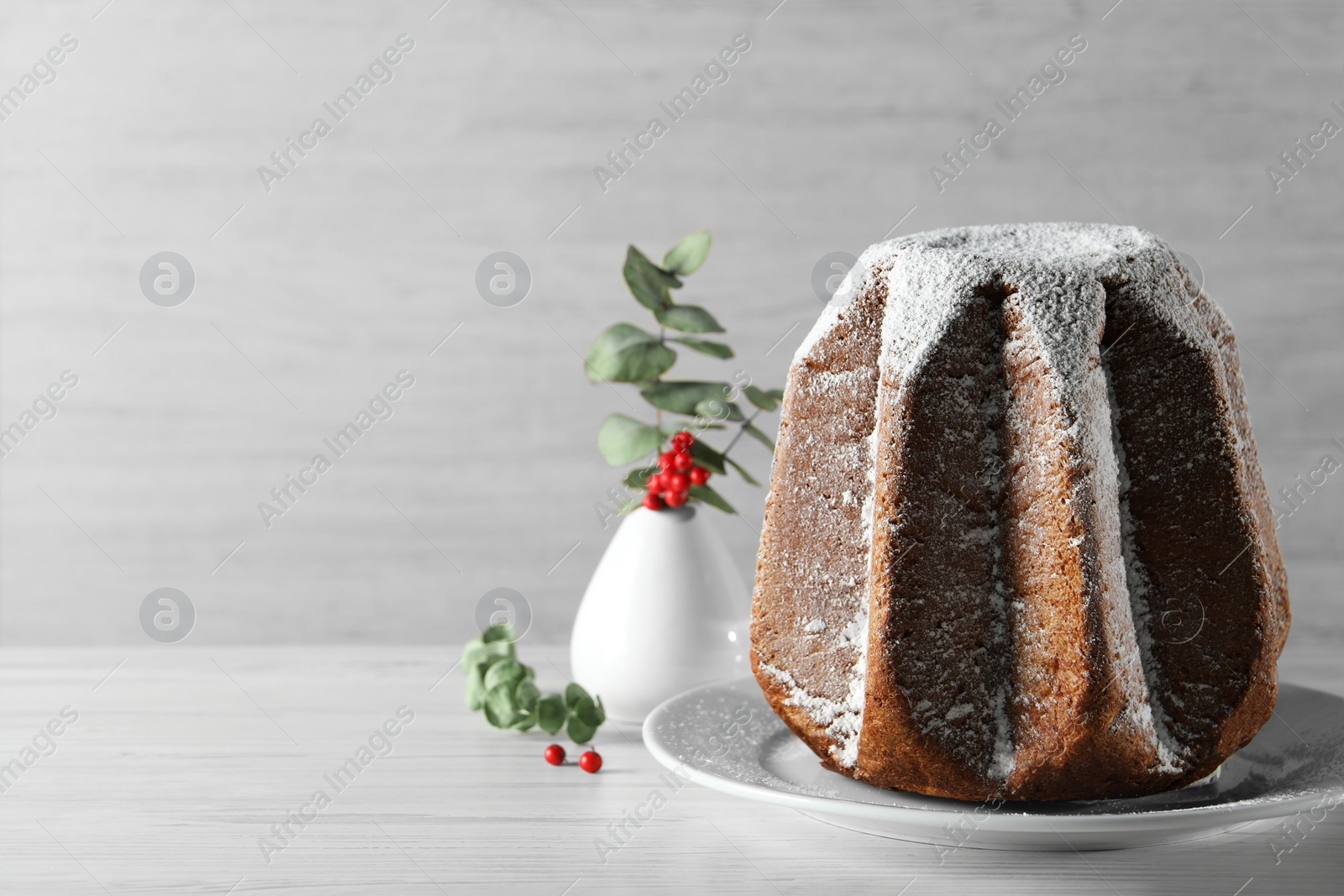 Photo of Delicious Pandoro cake decorated with powdered sugar on white wooden table, space for text. Traditional Italian pastry