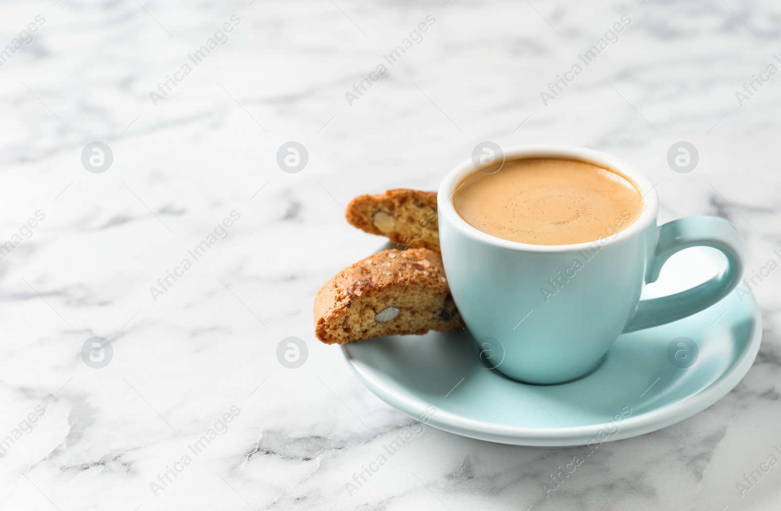 Photo of Tasty cantucci and cup of aromatic coffee on white marble table, space for text. Traditional Italian almond biscuits