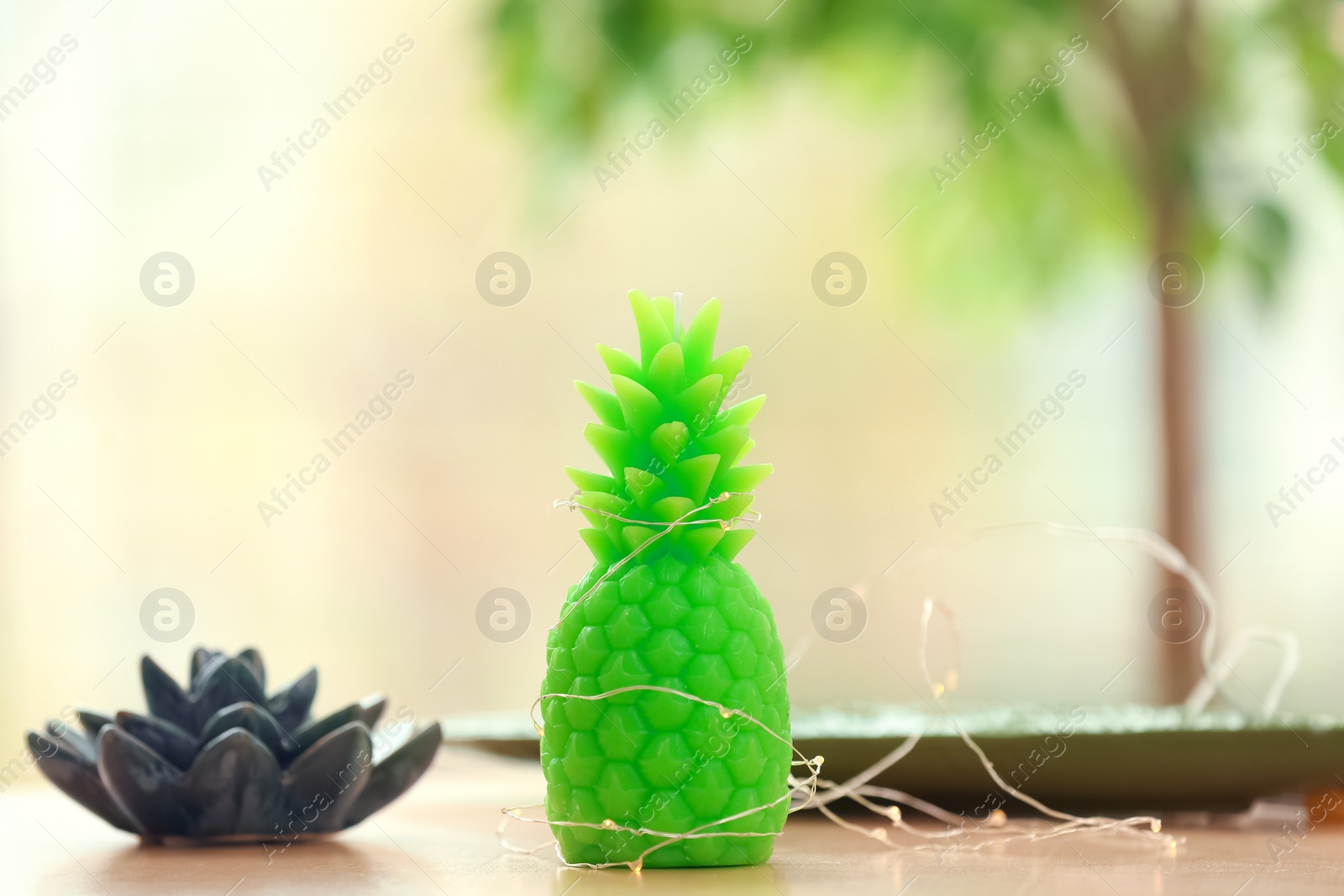 Photo of Stylish pineapple candle on table indoors. Home decorating idea