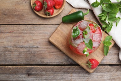Photo of Spicy strawberry cocktail with jalapeno and mint on wooden table, flat lay. Space for text