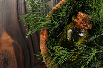 Photo of Bowl with bottle of essential oil and fresh dill on dark wooden table, top view. Space for text