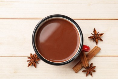 Photo of Tasty hot chocolate and spices on light wooden table, flat lay