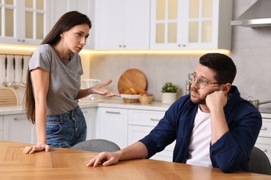 Photo of Wife blaming her husband in kitchen. Relationship problems