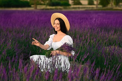 Beautiful young woman with bouquet sitting in lavender field