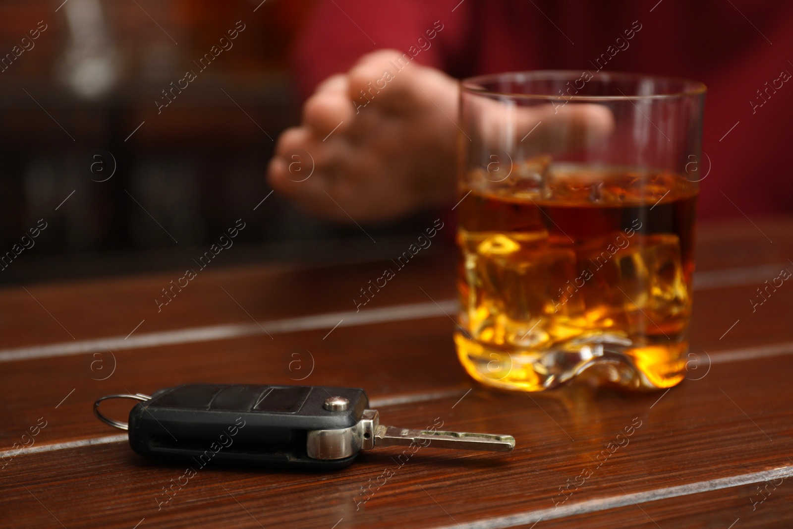 Photo of Man reaching for alcoholic drink at table with car keys, closeup. Don't drink and drive concept