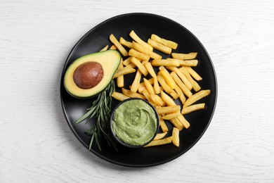 Plate with french fries, guacamole dip, rosemary and avocado served on white wooden table, top view