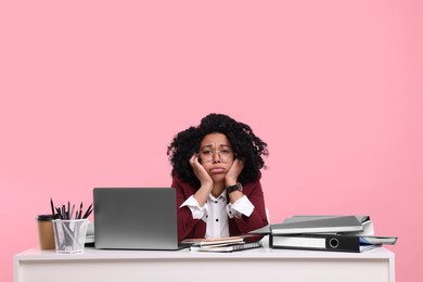 Stressful deadline. Exhausted woman sitting at white desk against pink background. Space for text
