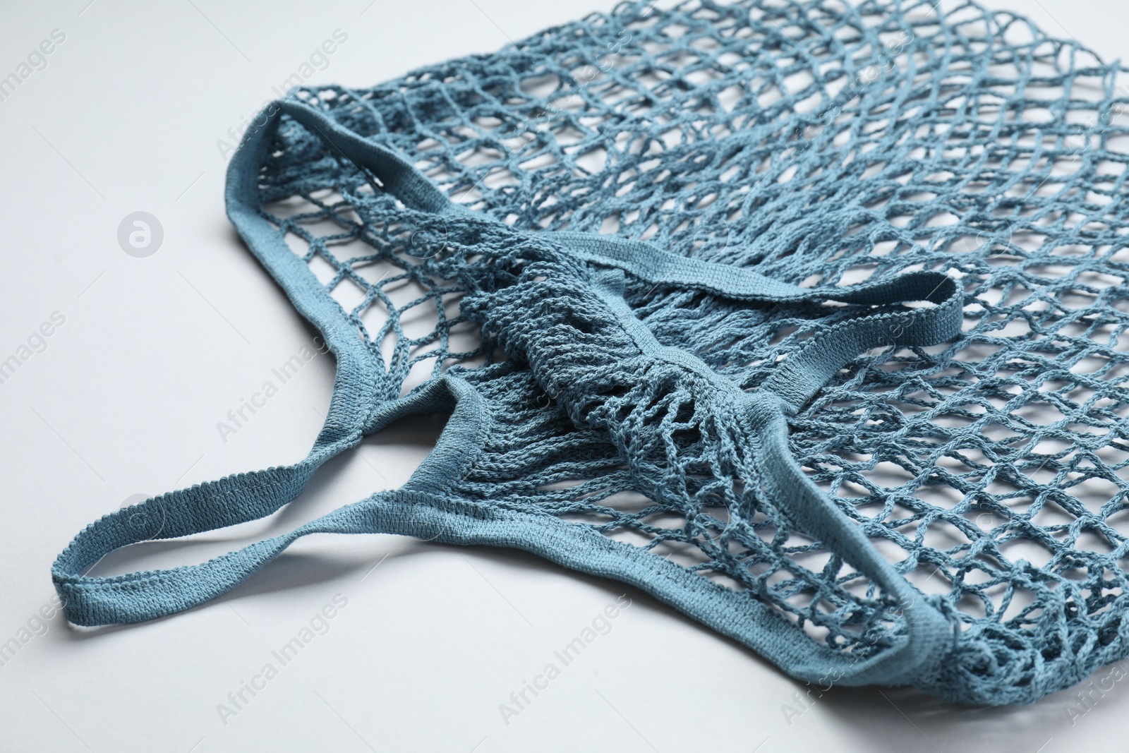 Photo of Blue string bag on light grey background, closeup