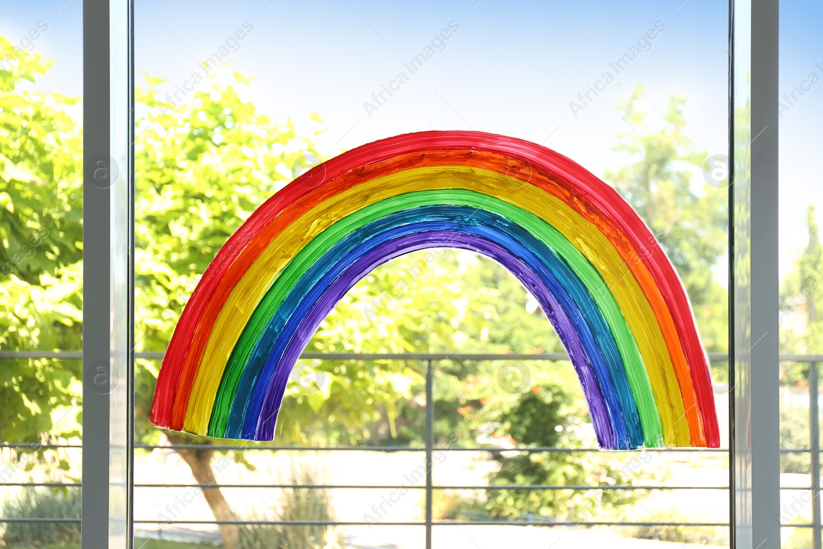 Photo of Picture of rainbow on window glass indoors. Stay at home concept