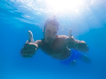 Handsome young man swimming in pool, underwater view