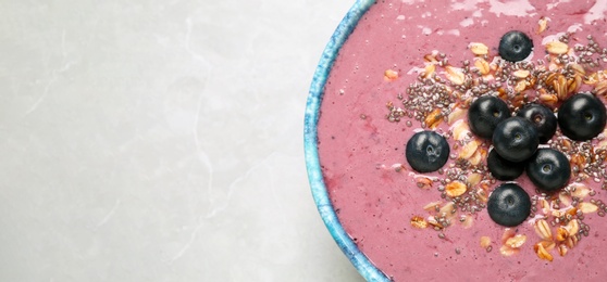 Delicious acai smoothie with granola and chia seeds in dessert bowl on grey table, top view. Space for text