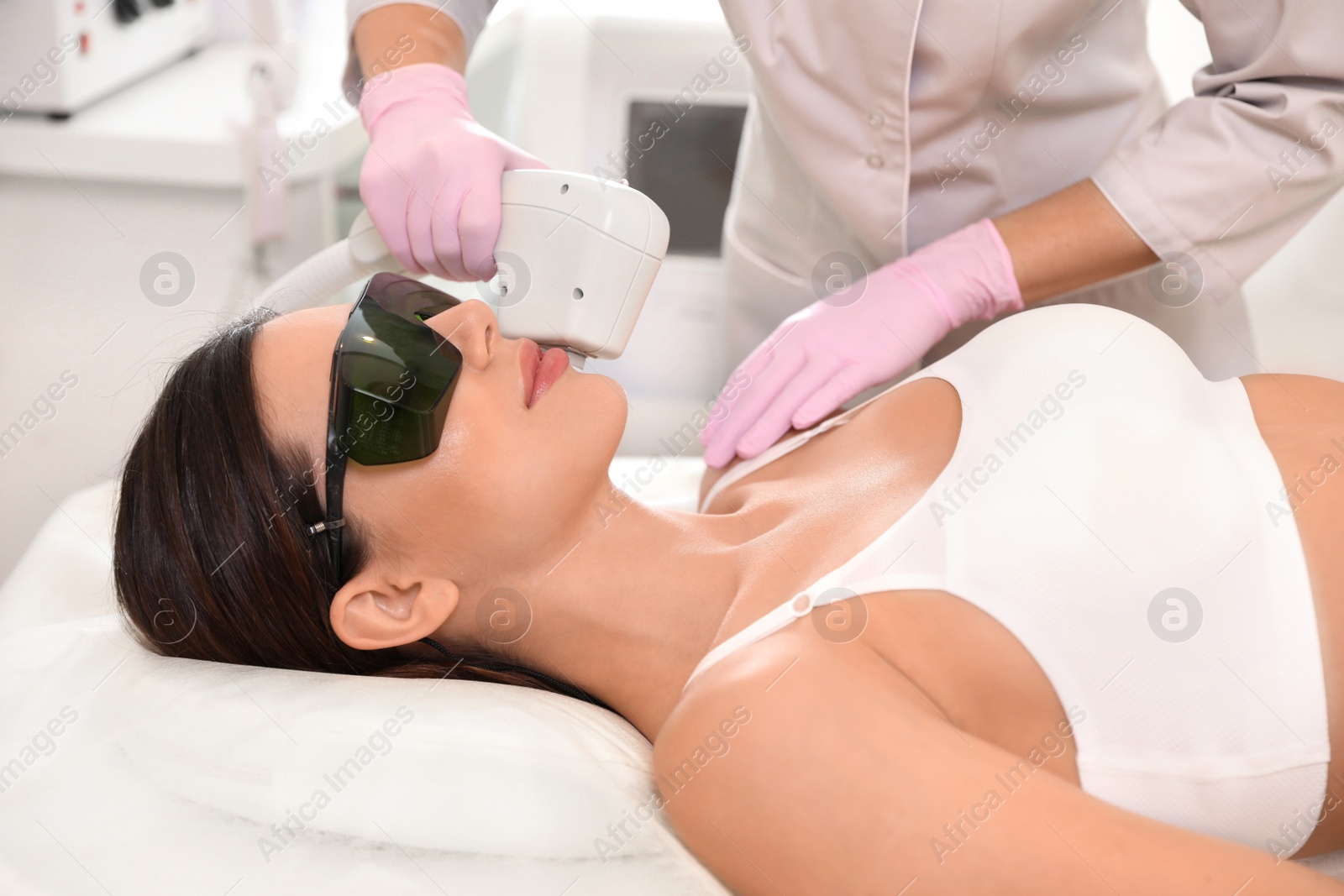 Photo of Young woman undergoing laser epilation procedure in beauty salon