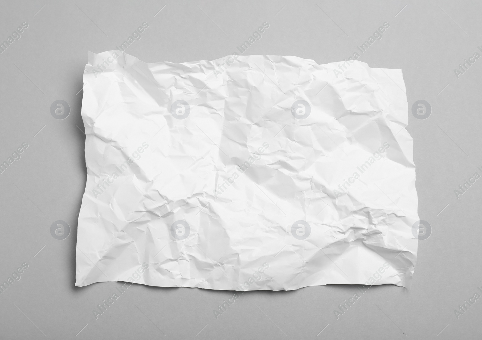 Photo of Sheet of white crumpled paper on grey background, top view