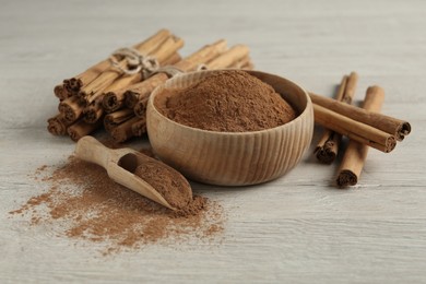Photo of Aromatic cinnamon powder and sticks on white wooden table