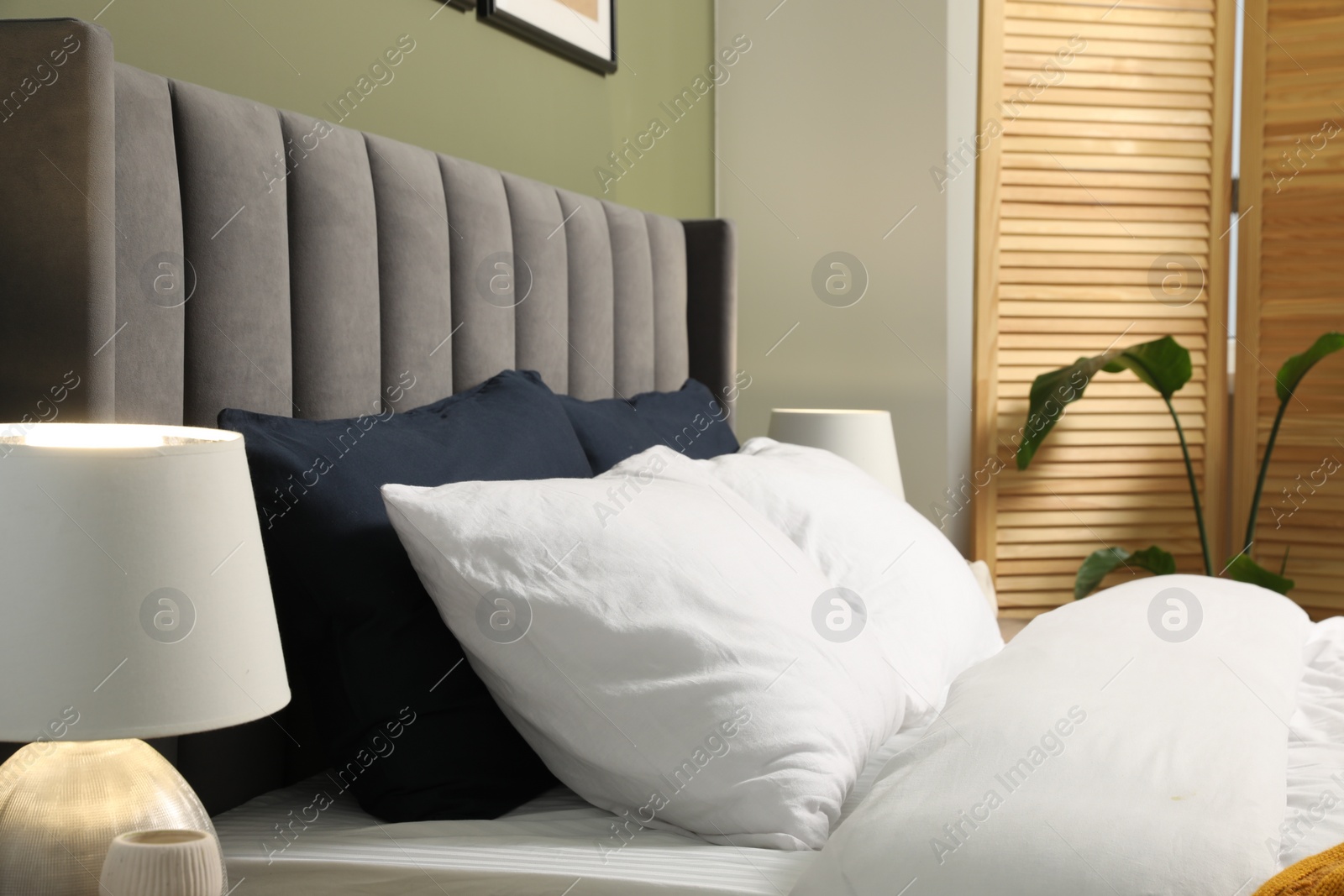 Photo of Comfortable bed with soft pillows in stylish room. Interior design